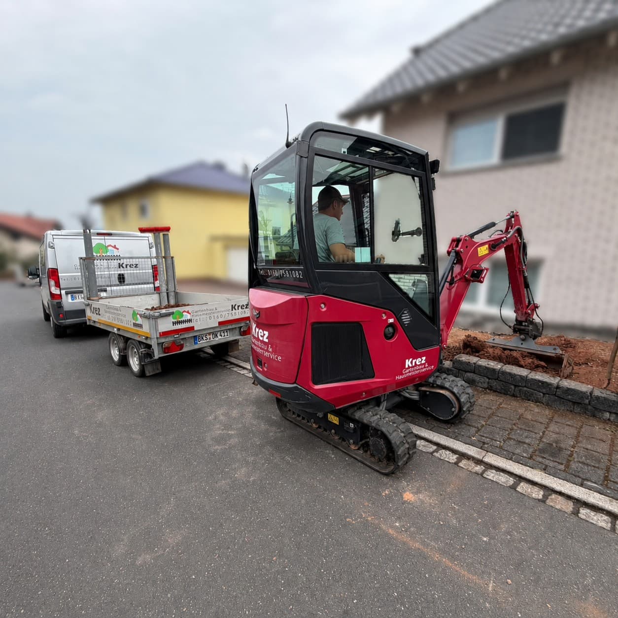 Minibagger bei Aushubarbeiten neben einem Transportanhänger