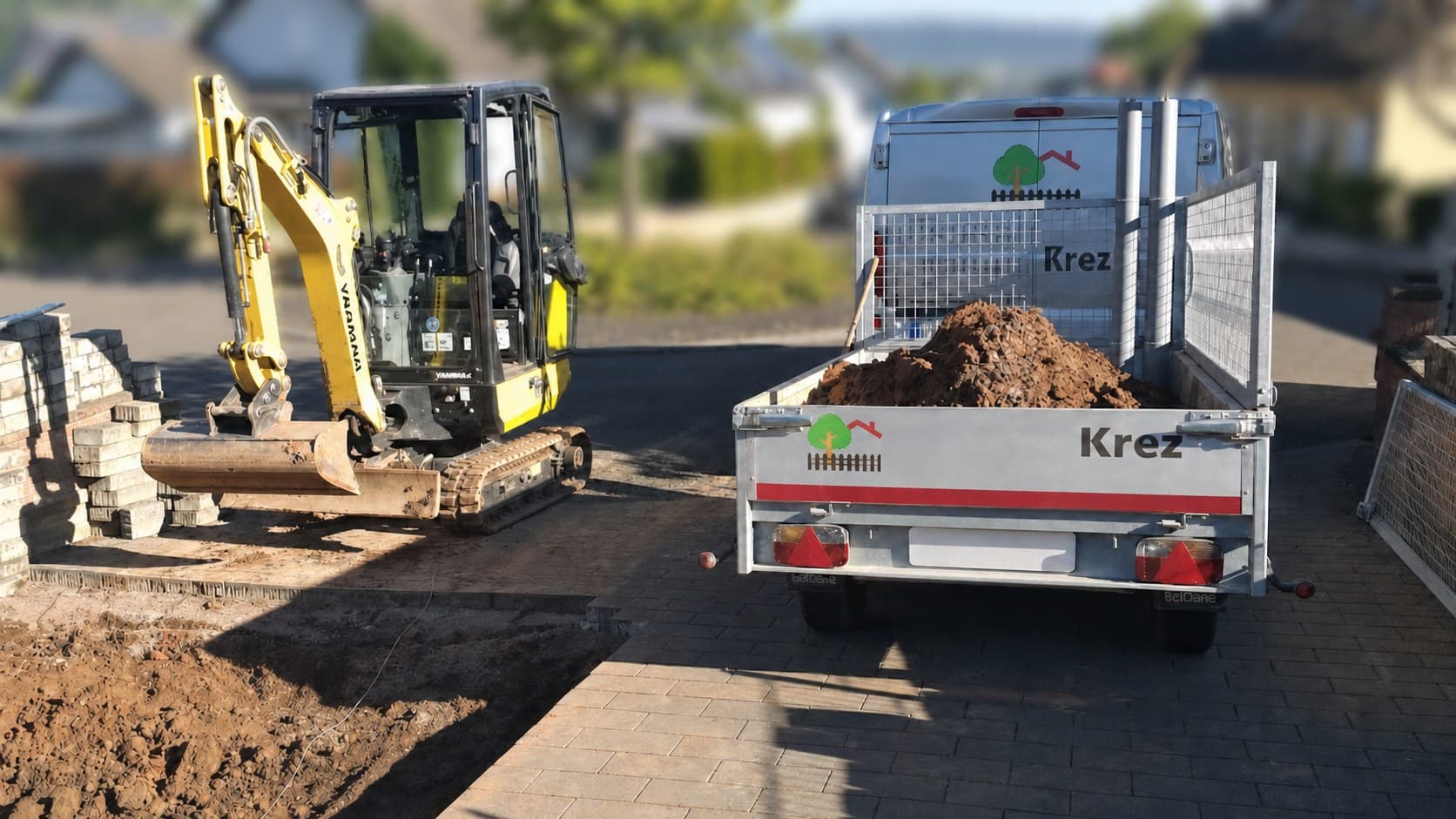 Minibagger und Anhänger bei Erdarbeiten in einem Zufahrtsbereich