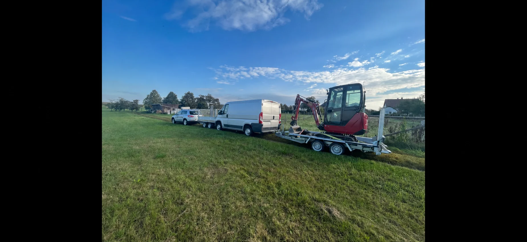 Fahrzeuge, Anhänger und Minibagger auf einer Wiese